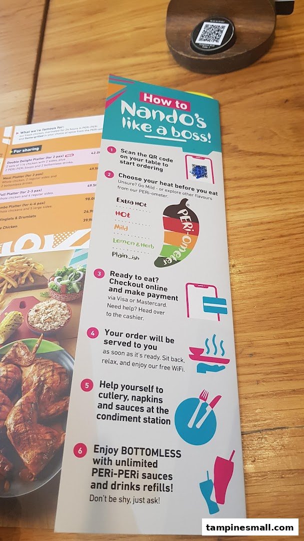 A Nando's table setting showing a menu, ordering guide, and a glimpse of flame-grilled PERi-PERi chicken.