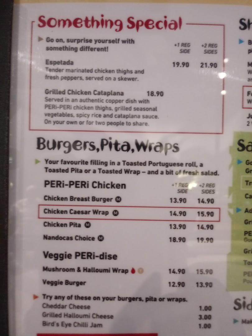 A close-up view of a Nando's menu displaying special dishes, burgers, pitas, wraps, and add-ons with prices.