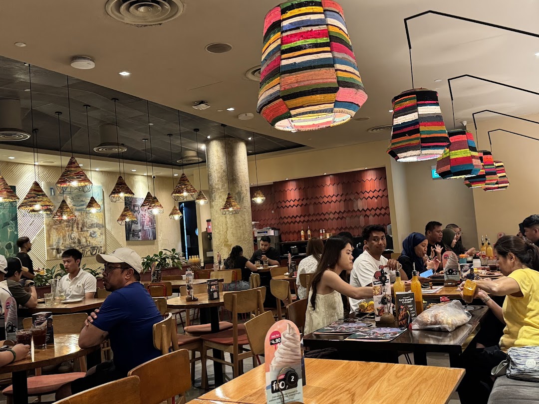 Diners enjoy meals in the vibrant, well-lit interior of Nandos, featuring unique colorful and woven light fixtures.