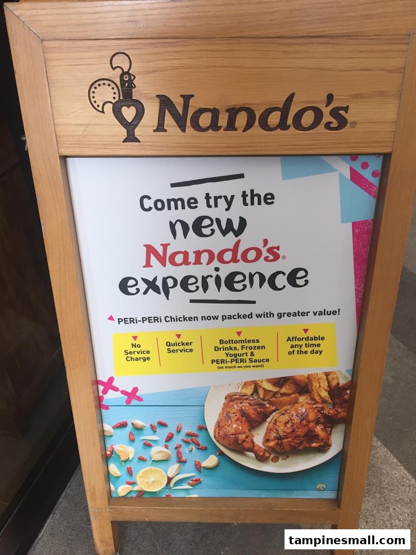An A-frame sign outside Nando's advertises their new PERi-PERi chicken experience with value-added benefits.