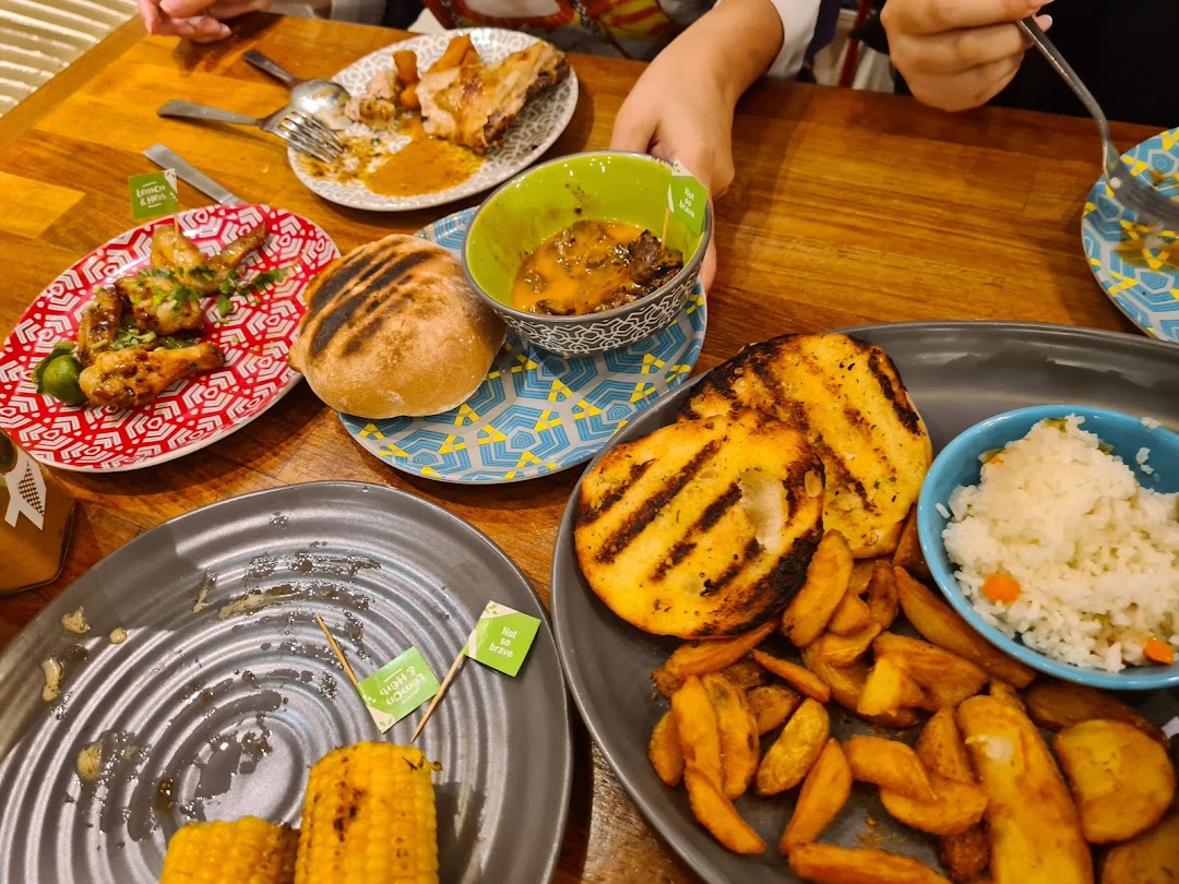A vibrant table spread at Nando's featuring flame-grilled chicken, various sides, and sauces, enjoyed by diners.