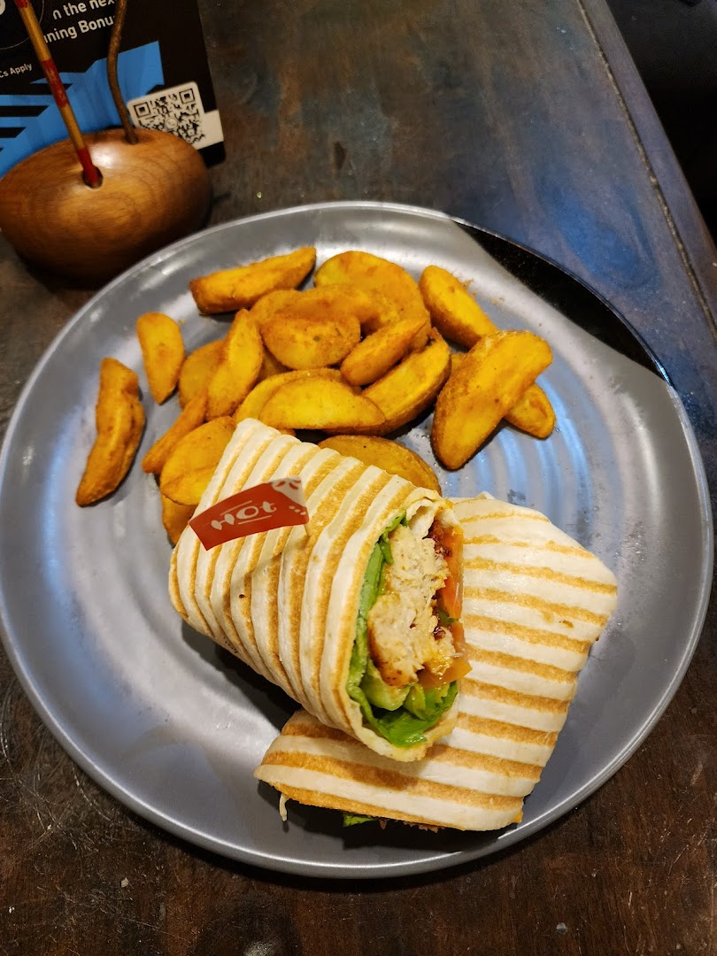 A delicious Nando's PERi-PERi chicken wrap served with golden potato wedges on a grey plate.
