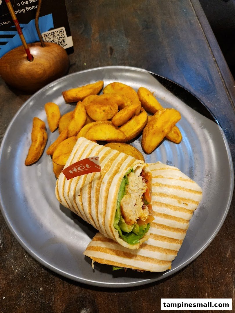 A delicious Nando's PERi-PERi chicken wrap served with golden potato wedges on a grey plate.