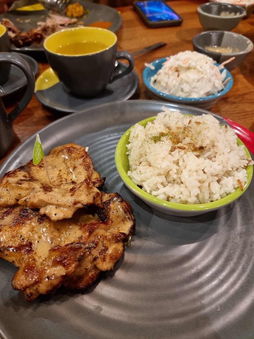 A delicious plate of flame-grilled chicken and rice, served with coleslaw and a drink at Nando's.