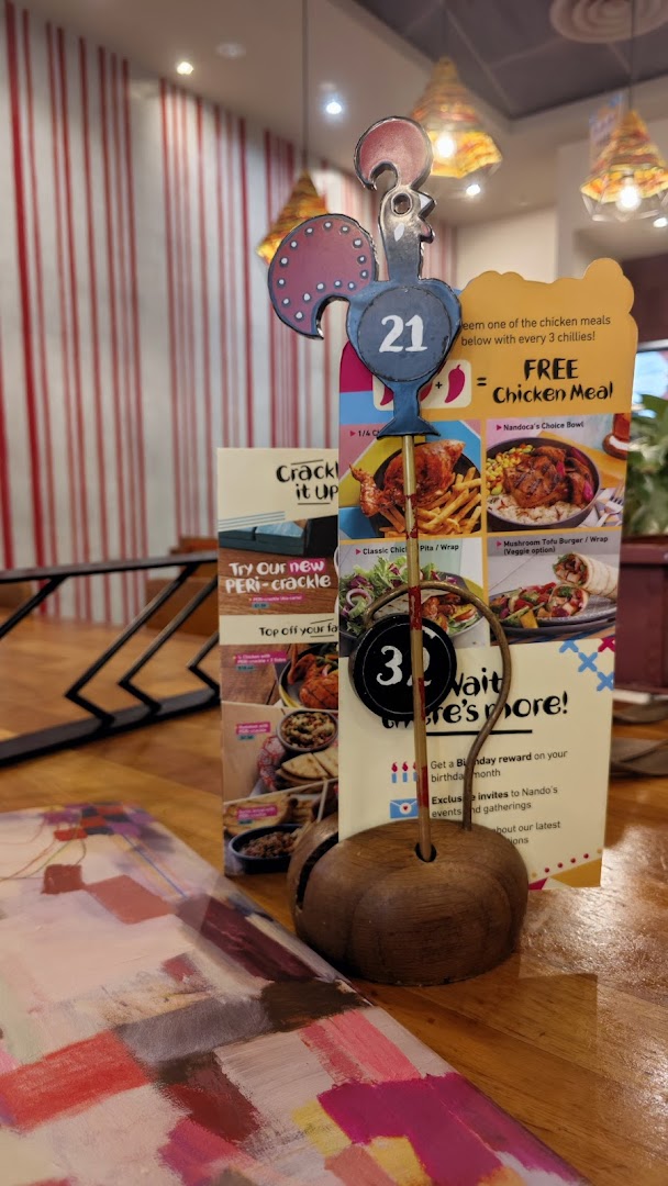 A Nando's table setting featuring a rooster-shaped table number and a promotional menu stand.