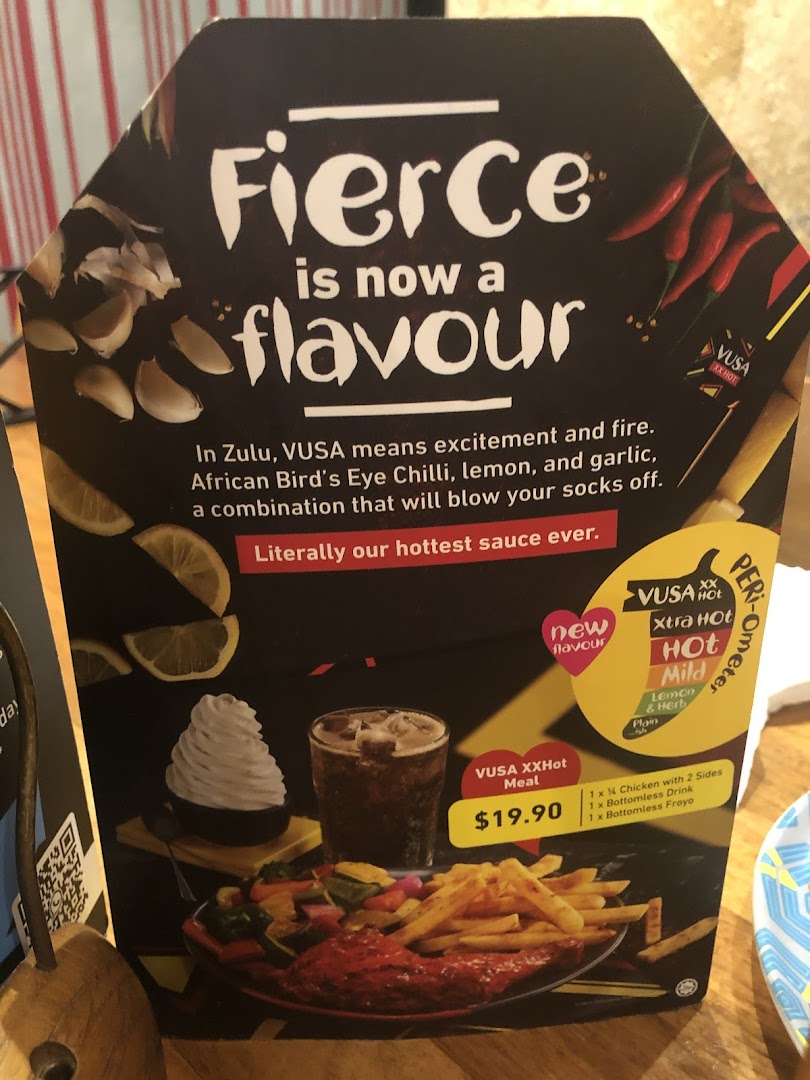 A Nando's menu board showcasing the new VUSA XXHot flavour and a meal deal with chicken, sides, drink, and froyo.