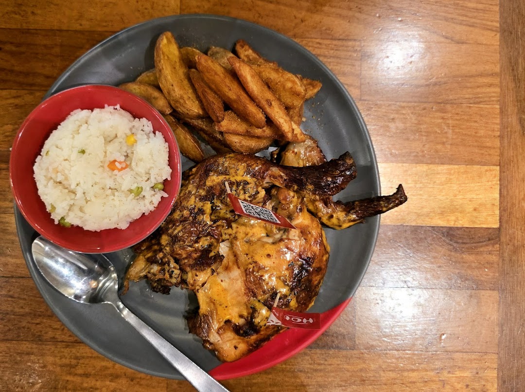 A delicious plate of Nando's flame-grilled PERi-PERi chicken with potato wedges and rice.
