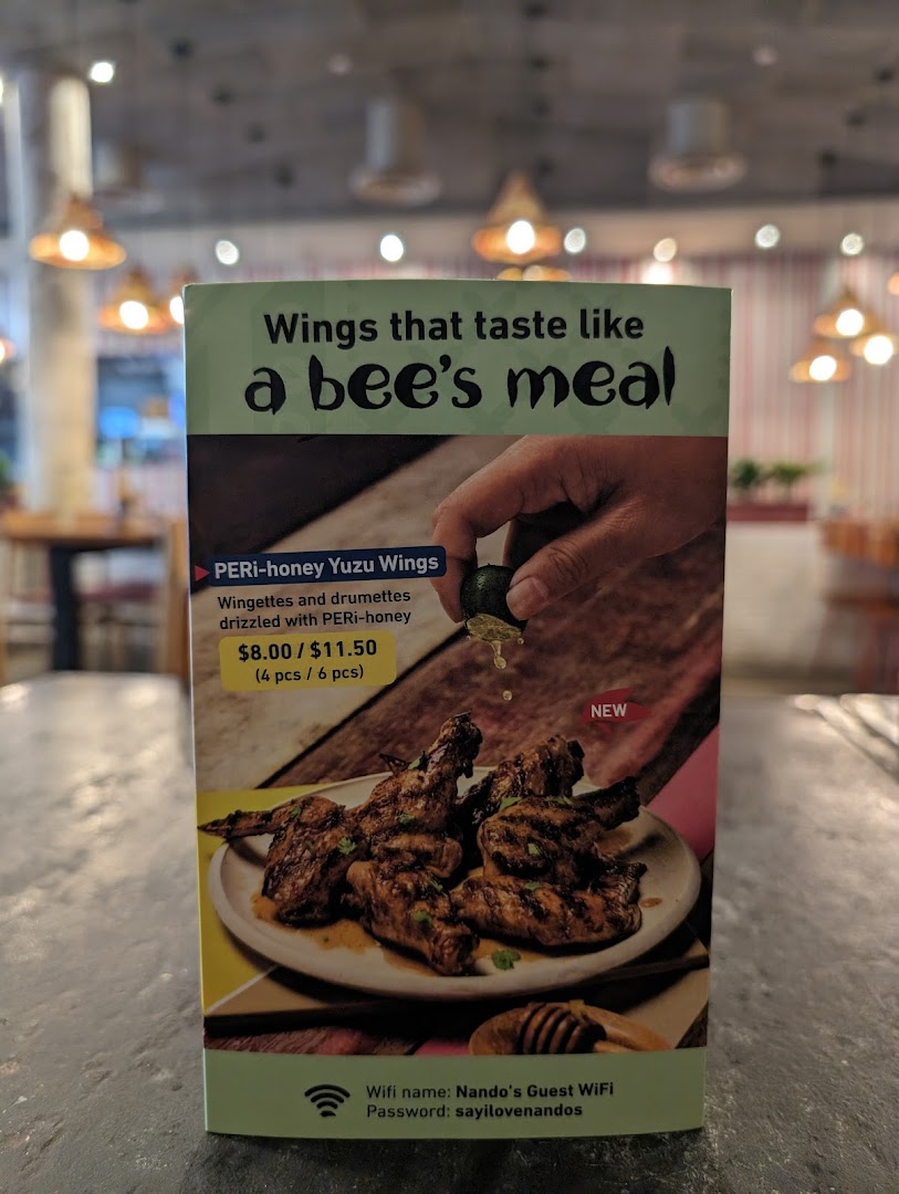 A promotional standee for Nando's PERi-honey Yuzu Wings, displaying pricing and guest WiFi information.