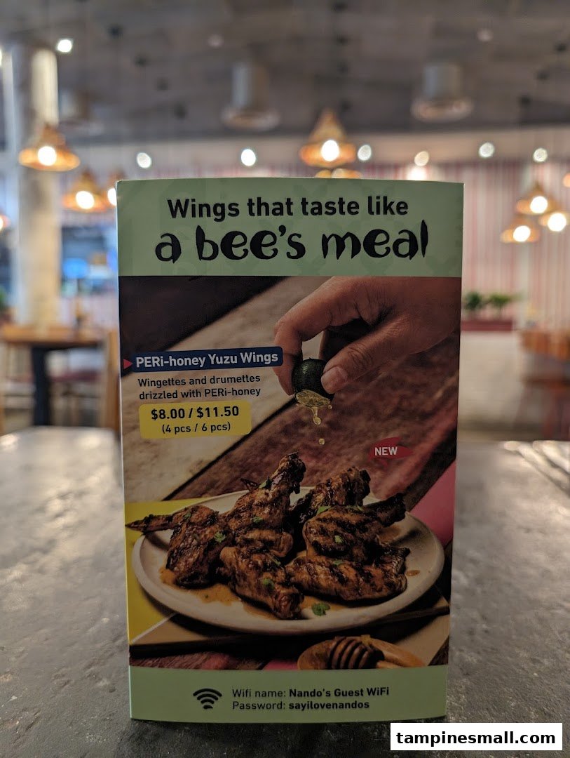 A promotional standee for Nando's PERi-honey Yuzu Wings, displaying pricing and guest WiFi information.