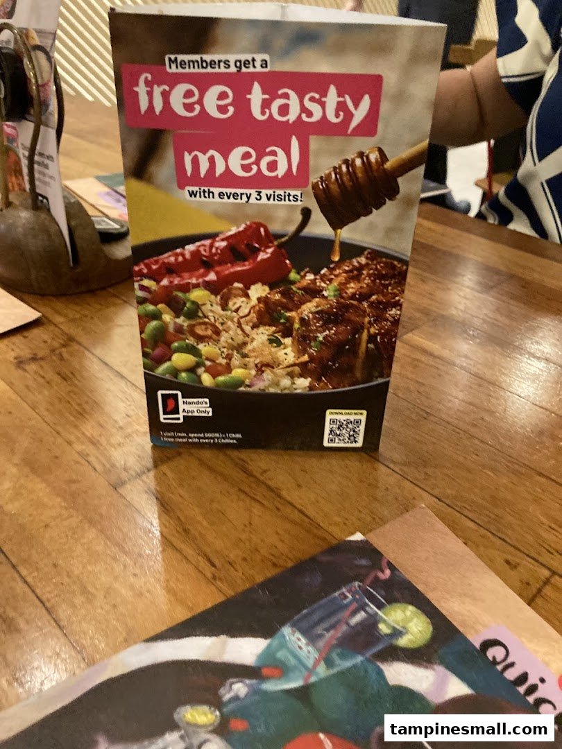 A Nando's table tent promoting a loyalty program for a free meal with every three visits.