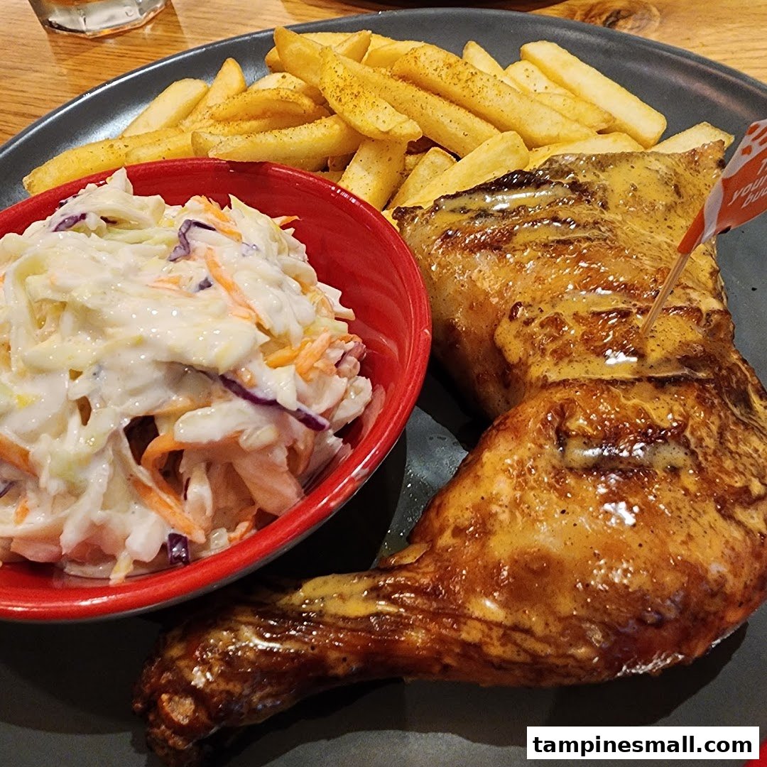 A plate of Nando's flame-grilled PERi-PERi chicken with fries and creamy coleslaw.
