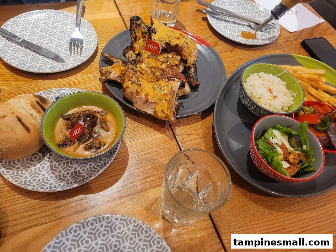 A table laden with Nando's flame-grilled PERi-PERi chicken, rice, fries, salad, and a mushroom dish, ready for a delicious meal.