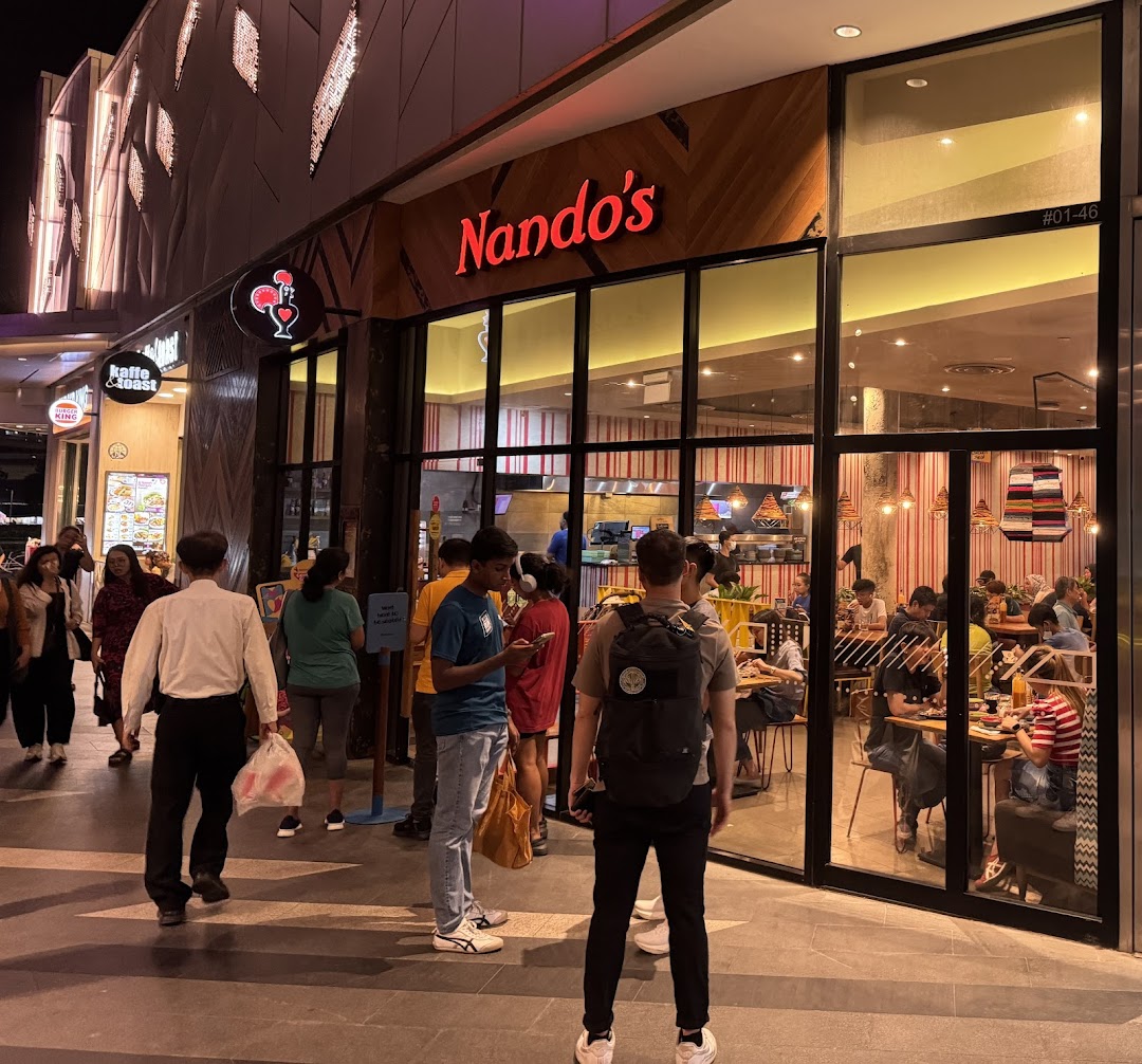 Nando's Tampines Mall shopfront at night, showcasing its vibrant interior and customers.