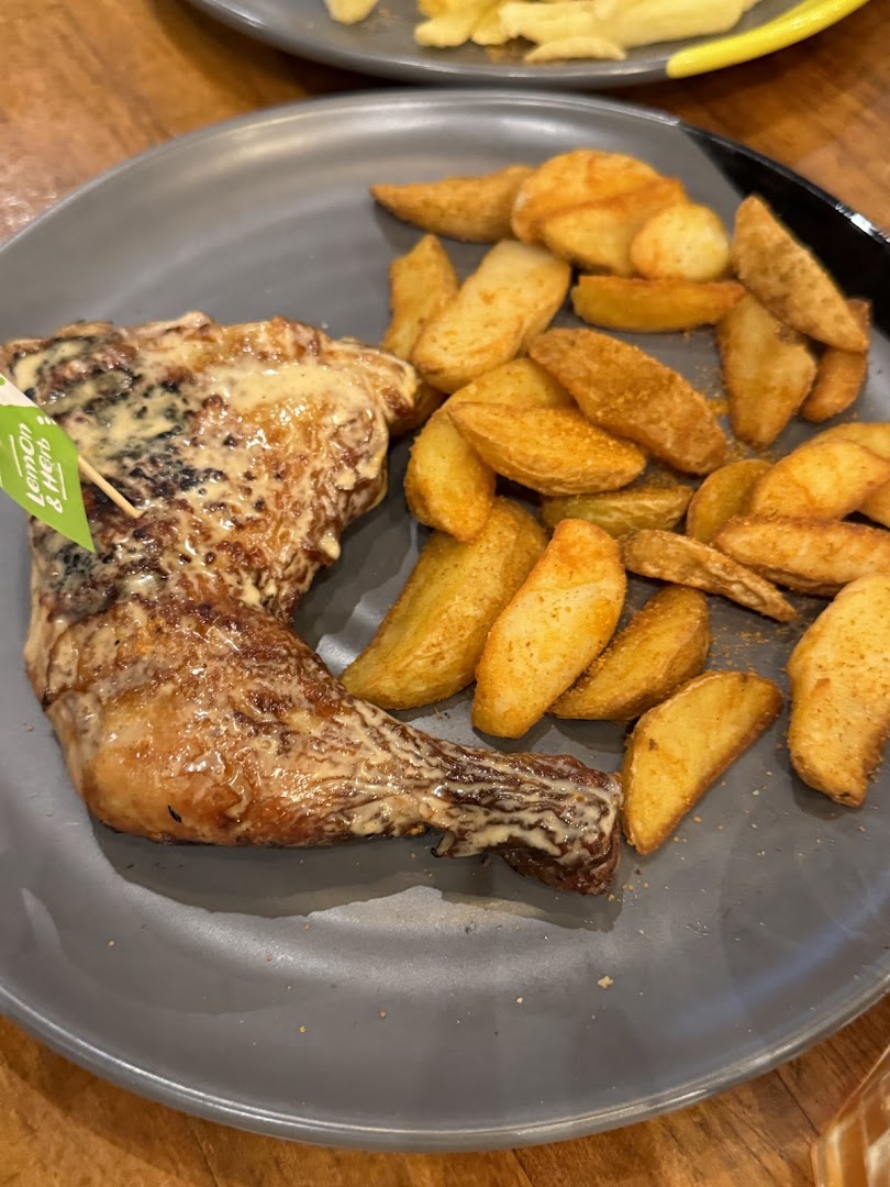 A plate of flame-grilled PERi-PERi chicken with creamy sauce and seasoned potato wedges.