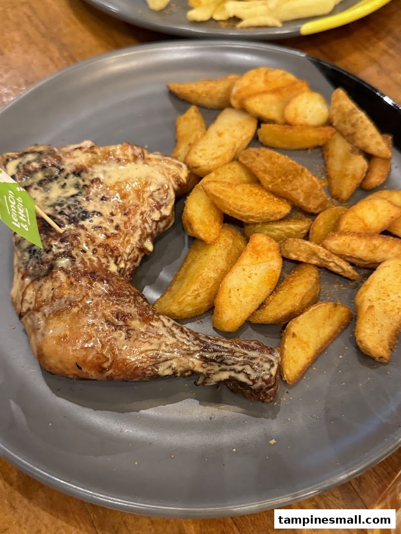 A plate of flame-grilled PERi-PERi chicken with creamy sauce and seasoned potato wedges.