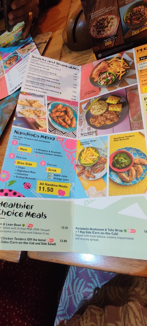 A close-up view of Nandos' in-restaurant menu, displaying various food categories and prices.