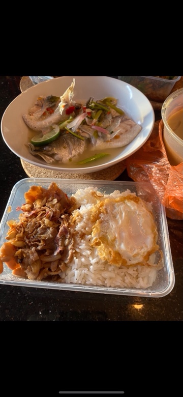 A delicious spread of Thai dishes, including steamed fish and a rice dish with fried egg and savory toppings.