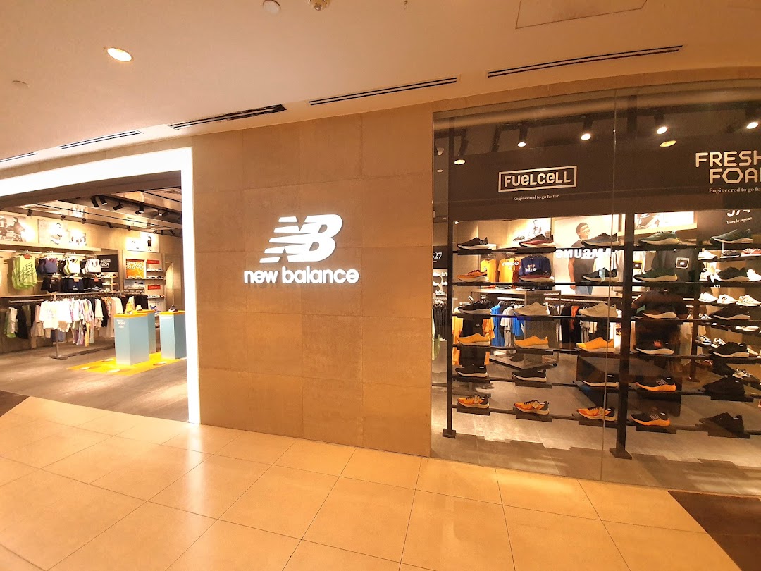 The New Balance store entrance featuring its prominent logo and a vibrant display of athletic footwear and apparel.