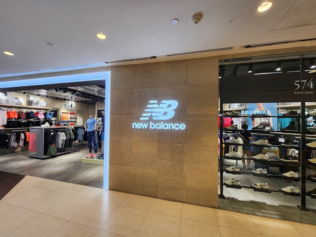 The New Balance store entrance features a prominent logo, showcasing athletic apparel and footwear displays.