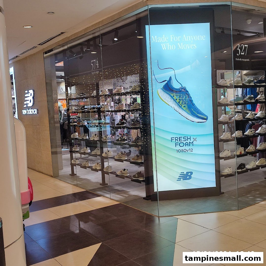 The New Balance shop front features a prominent logo, display windows showcasing numerous shoes, and a large digital advertisement.