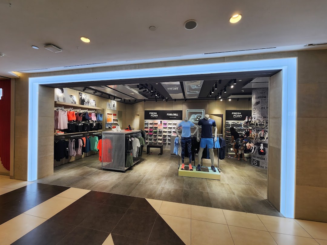 The New Balance store entrance showcases athletic apparel, footwear, and mannequins in a well-lit interior.