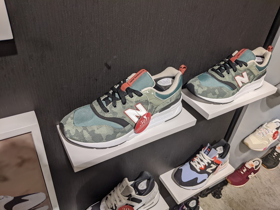 New Balance sneakers displayed on shelves, showcasing various styles and colors in a retail setting.