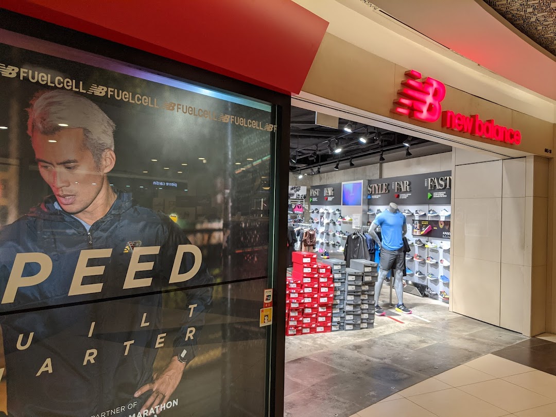 The New Balance store entrance features a large promotional poster and an inviting view of athletic footwear and apparel.