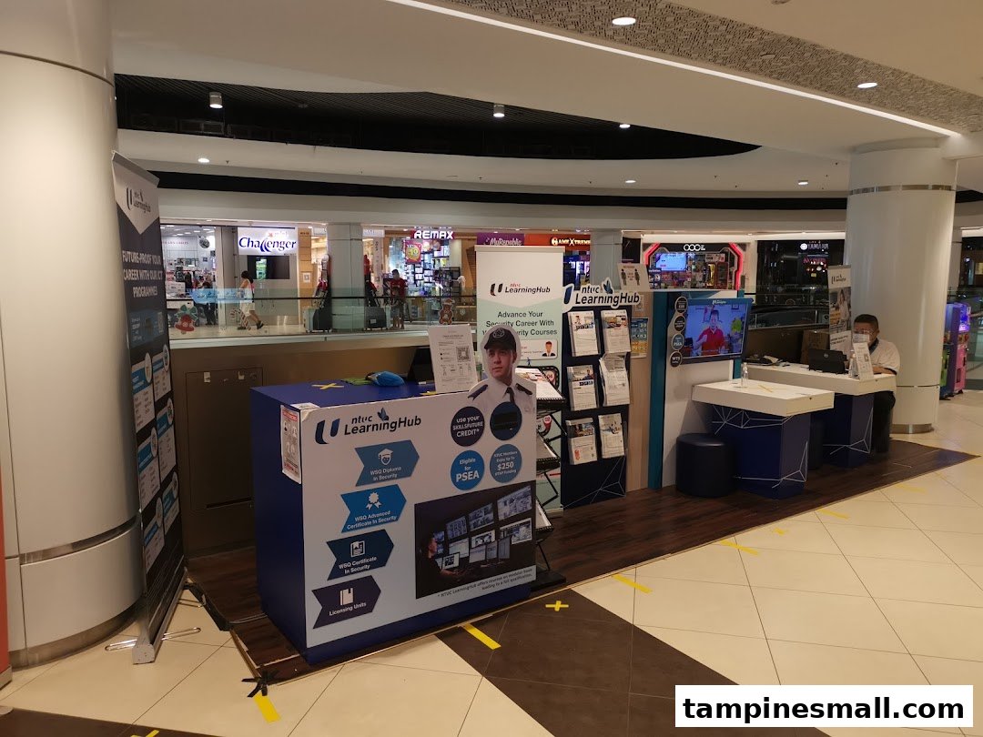 An NTUC LearningHub booth in a shopping mall, featuring promotional materials, a display, and staff.
