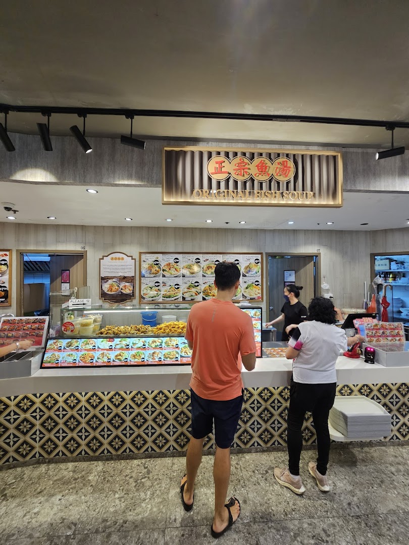 Customers order at the counter of Original Fish Soup, showcasing food displays and menu boards.