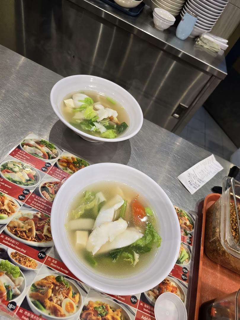 Two bowls of fresh fish soup are served on a counter, with a detailed menu visible.