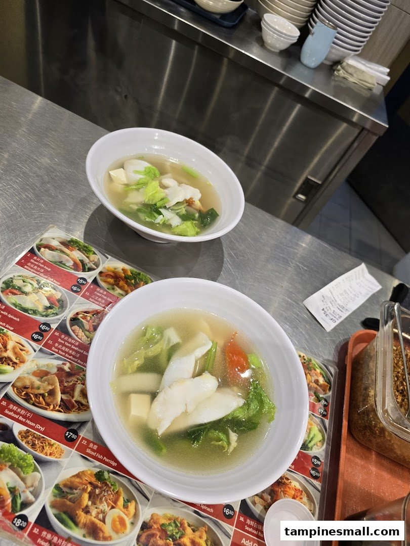 Two bowls of fresh fish soup are served on a counter, with a detailed menu visible.