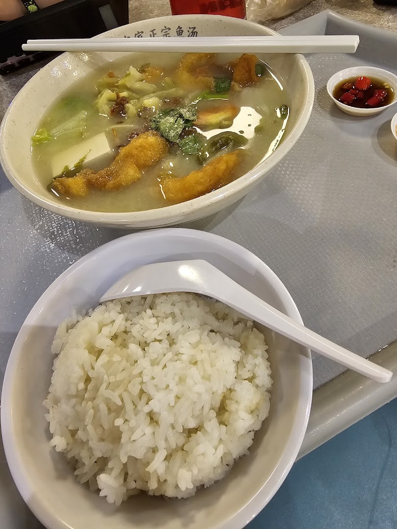 A delicious bowl of fish soup with fried fish, tofu, and vegetables, served with a side of white rice.
