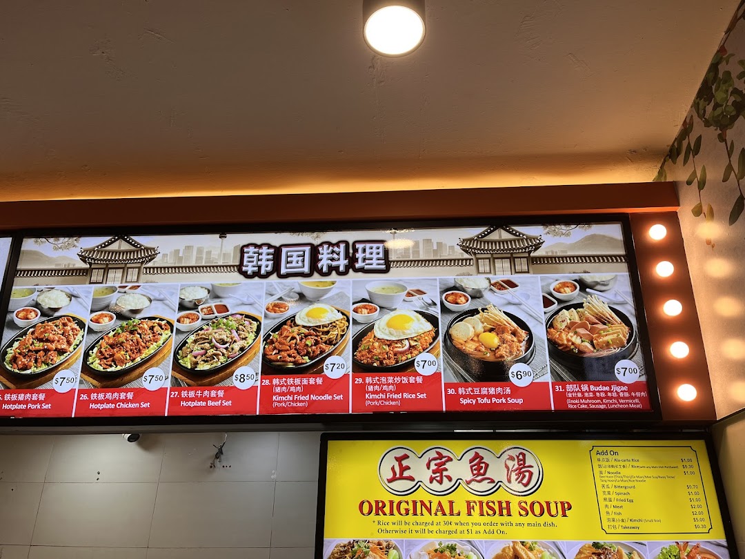 A brightly lit menu board displaying Korean hotplate dishes, soups, and an 'Original Fish Soup' add-on list.