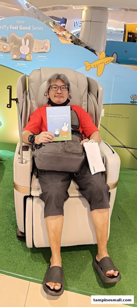 A man relaxes in an OSIM massage chair, holding a Miffy-themed booklet, showcasing wellness products.