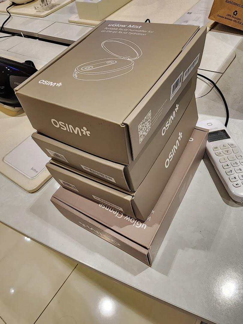 A stack of OSIM uGlow Mist and uGlow Cleanse product boxes on a counter.