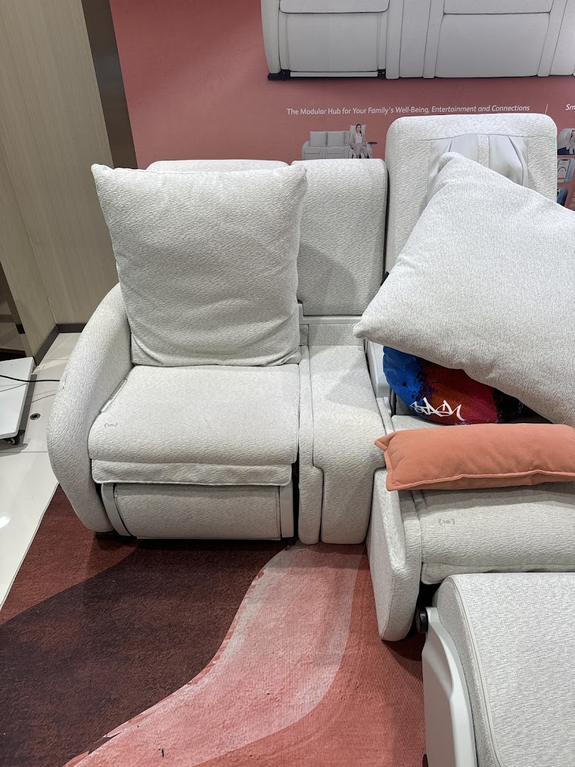 A comfortable, modular massage sofa system displayed in an OSIM store, featuring light upholstery and cushions.