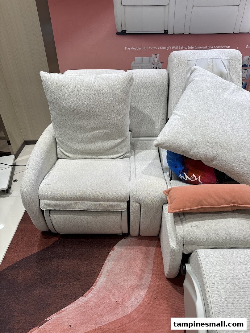 A comfortable, modular massage sofa system displayed in an OSIM store, featuring light upholstery and cushions.