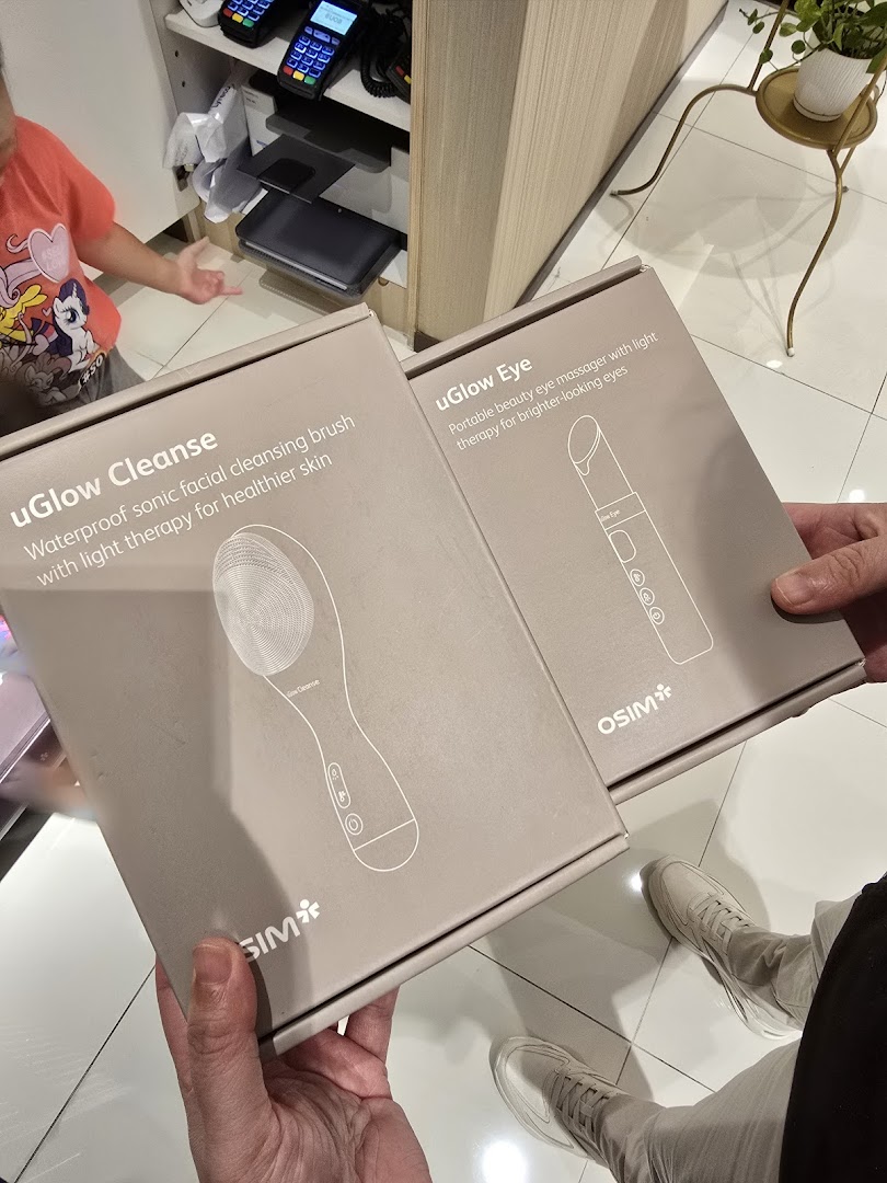 Hands hold OSIM uGlow Cleanse and uGlow Eye product boxes, showcasing advanced beauty devices.