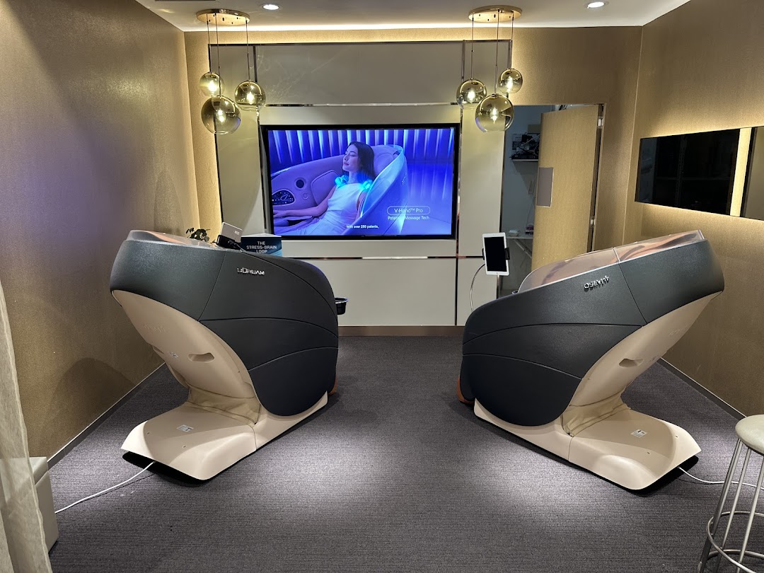 Two modern OSIM massage chairs displayed in a showroom with a large screen showcasing product features.