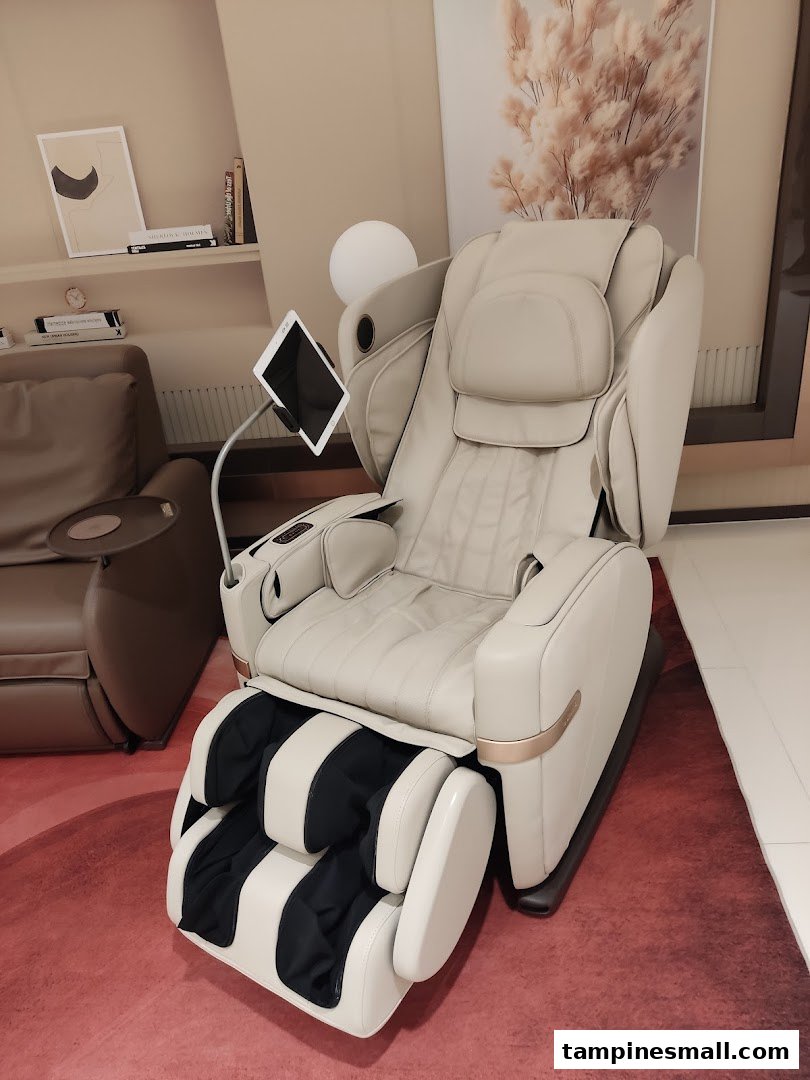 A luxurious beige OSIM massage chair with an attached tablet stand, displayed in a modern showroom.