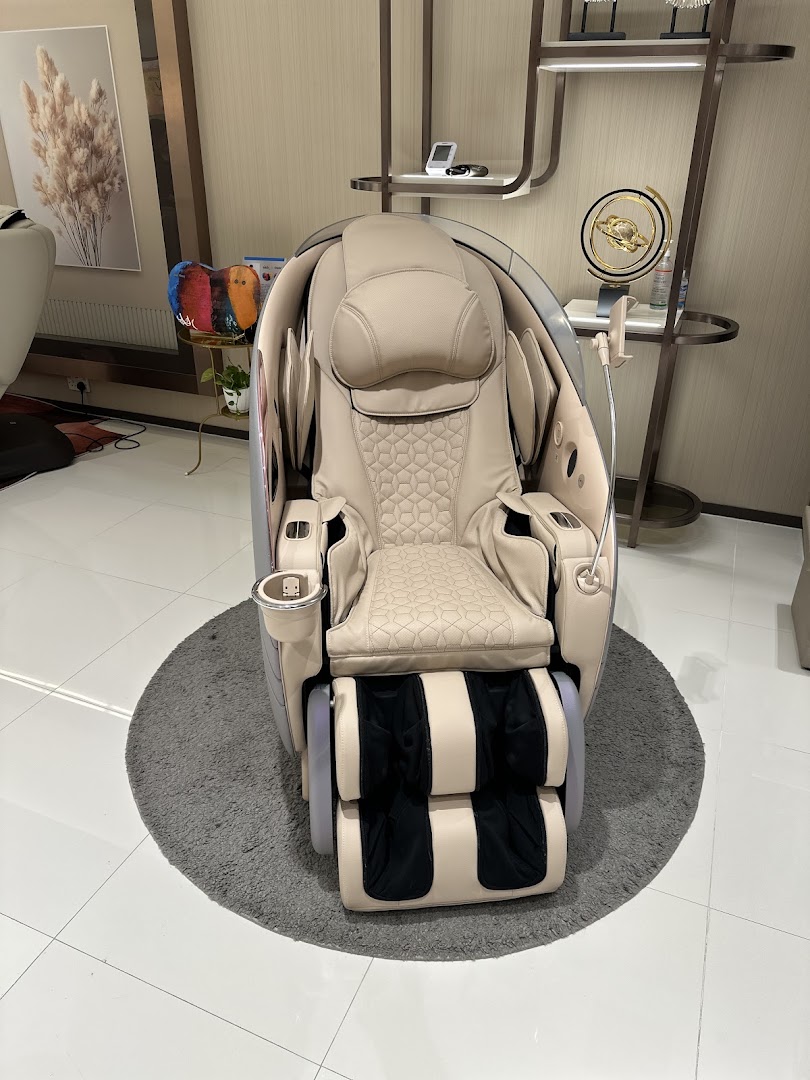 A luxurious beige massage chair with intricate patterns sits on a grey rug in a modern showroom.