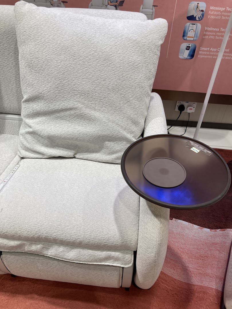 A comfortable light grey massage chair with an attached side table and product feature display.