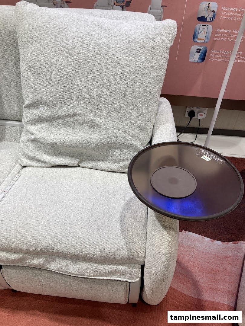A comfortable light grey massage chair with an attached side table and product feature display.
