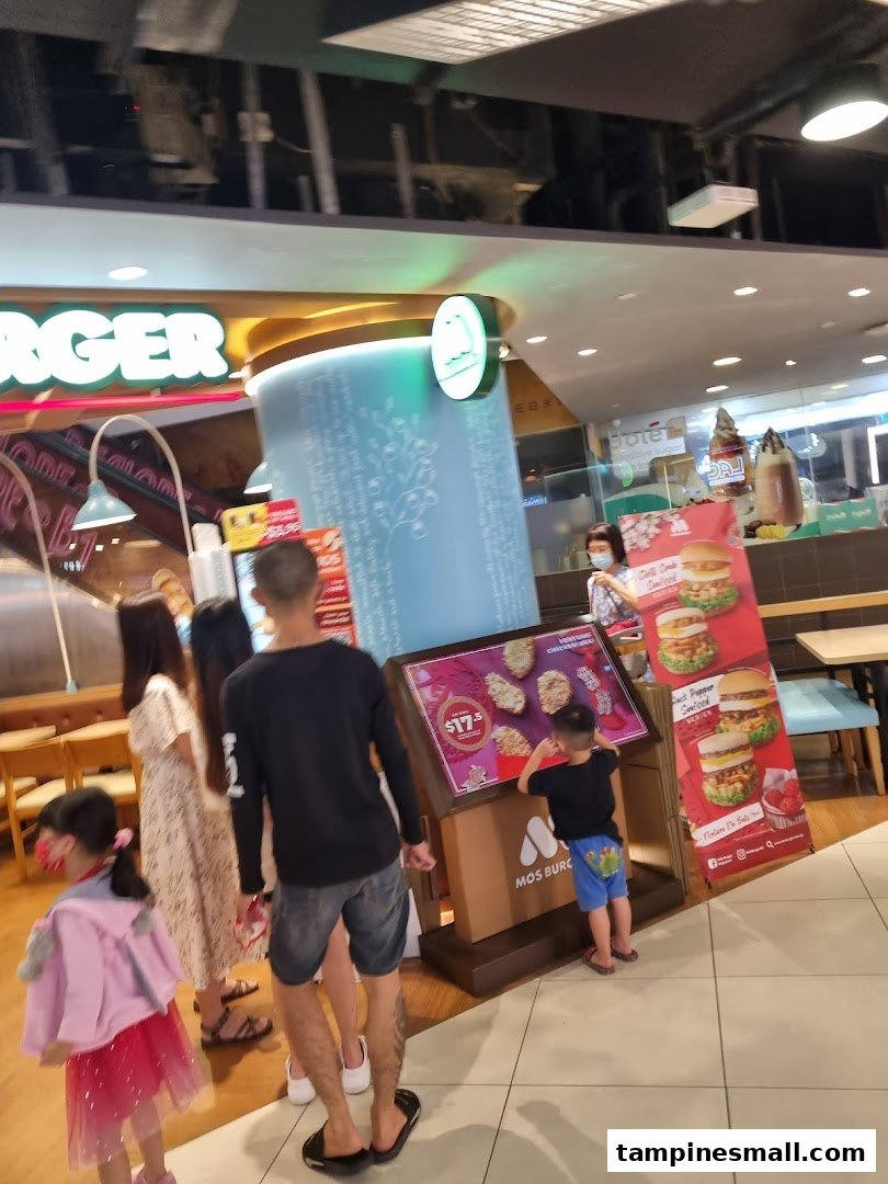 Customers browse promotional displays at a vibrant MOS Burger outlet within a shopping mall.