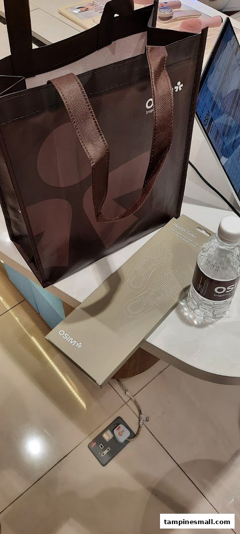 An OSIM shopping bag, Health Soles product, and branded water bottle on a display table inside the shop.