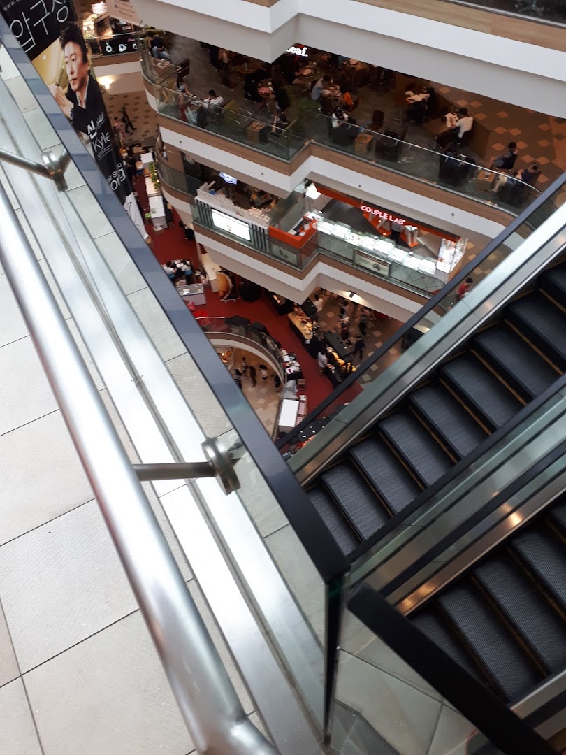An aerial view of a multi-level shopping mall interior with escalators and various shops.