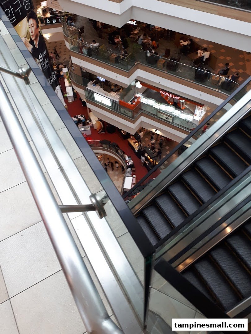 An aerial view of a multi-level shopping mall interior with escalators and various shops.