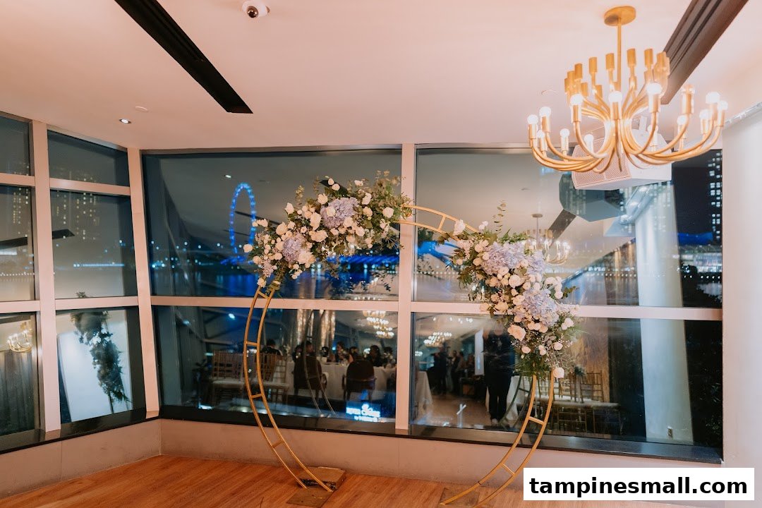 An elegant event space featuring a floral arch, large windows overlooking a city night view, and a golden chandelier.