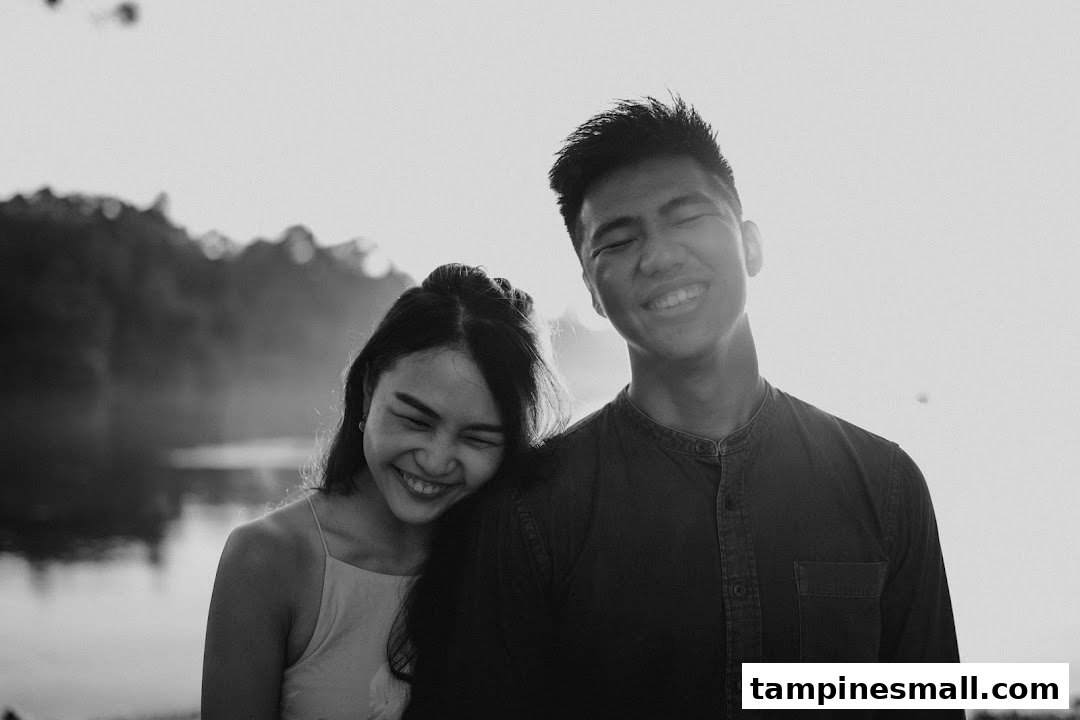 A black and white photo of a happy couple smiling outdoors, likely a pre-wedding or engagement shoot.