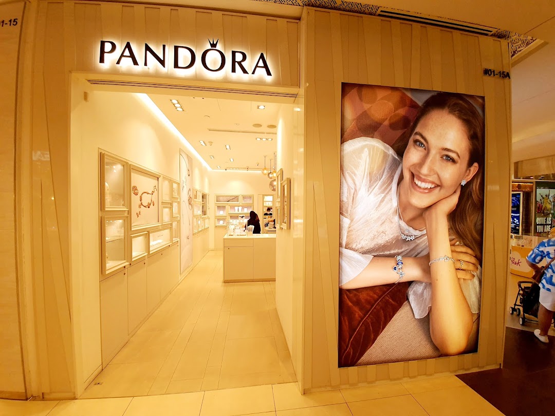 The illuminated entrance of a Pandora jewelry store featuring a large promotional display.